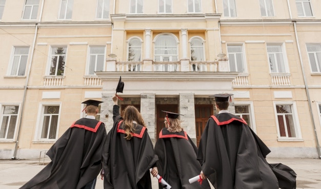 Alunos formados e comemorando em frente à faculdade