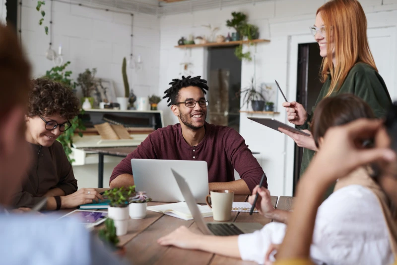 Pessoas à mesa de trabalho sorrindo.