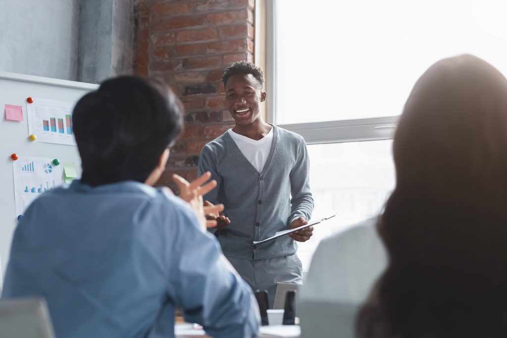 Rapaz dando instruções a um homem e uma mulher com expressão de satisfação no rosto. Sucesso do Estudante.