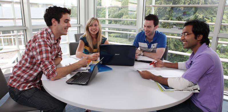 Pessoas conversando à mesa, trabalhando em equipe. Estudar em Galway.