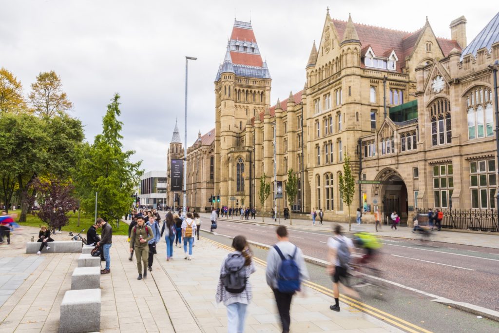 Estudantes e transeuntes na fachada da Universidade de Manchester