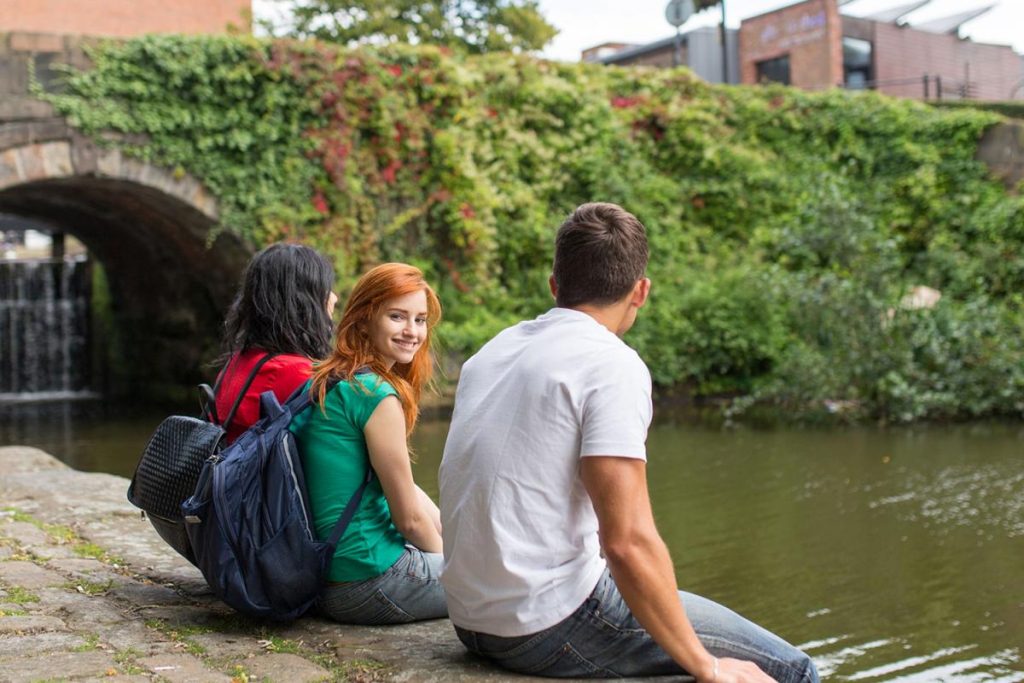 Três pessoas à beira de um lago na cidade de Manchester