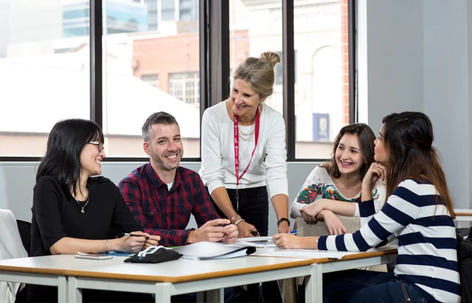 Alunos sentados à mesa com professora | Curso pathway