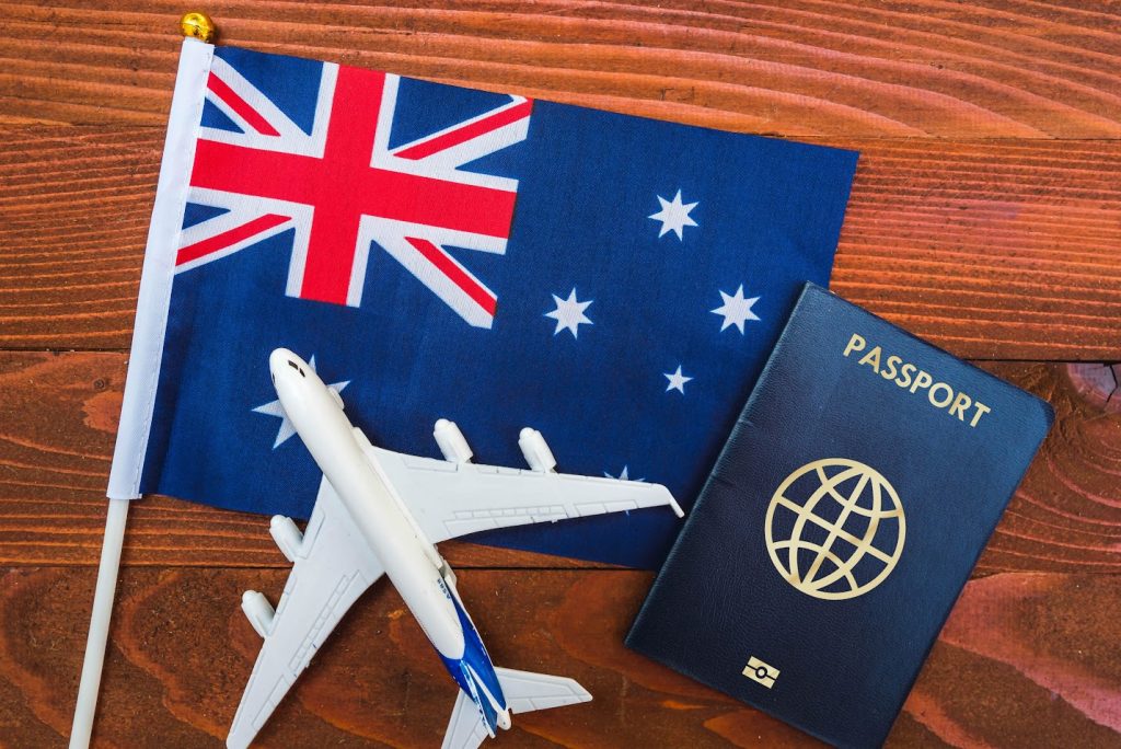 Passaporte e avião em miniatura sobre bandeira pequena da Austrália | Renovação de visto australiano