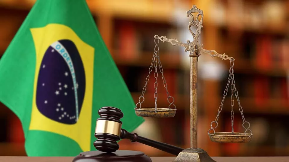 Bandeira do Brasil ao lado de uma balança da justiça e um martelo | Direito no exterior