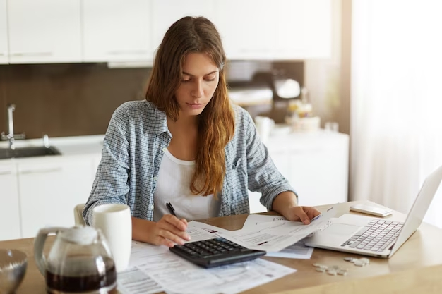 Mulher fazendo cálculos na frente do computador | Bolsa de estudo no exterior